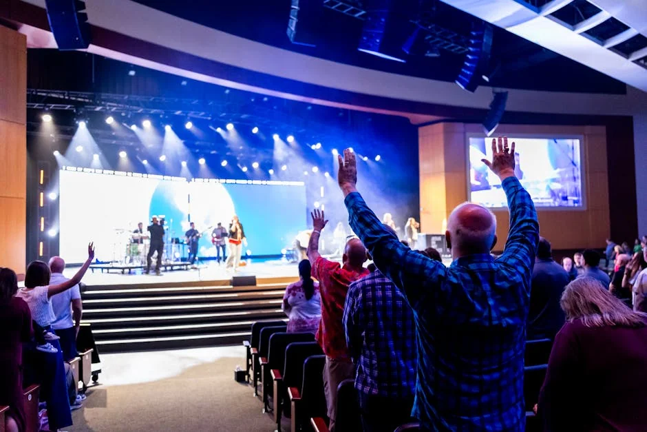 A lively worship service with an audience raising hands to a live band on stage in a church. - churchled wall price