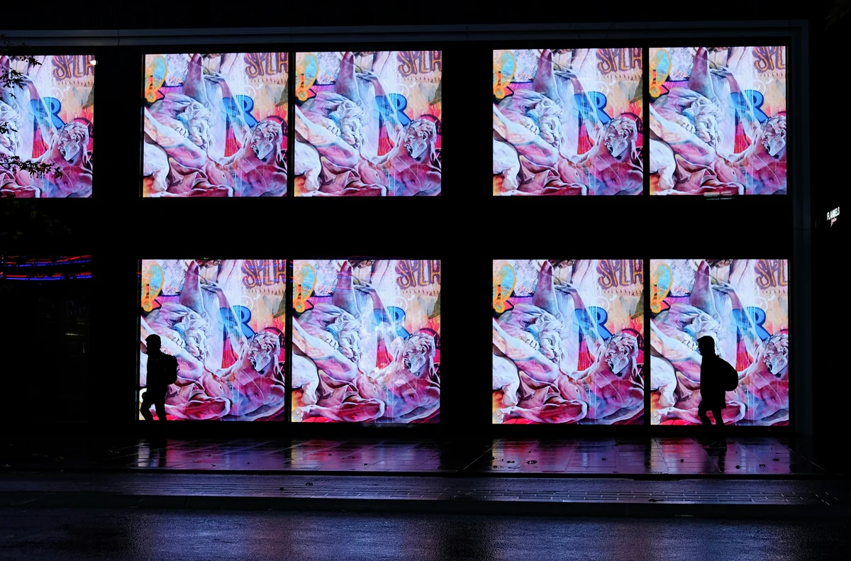 two persons walking beside building with LED artworks - foldable led screen