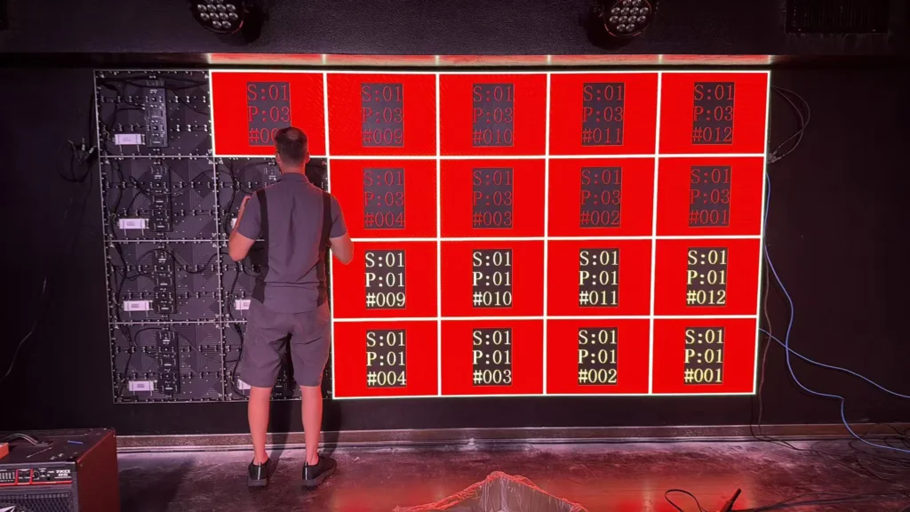 a indoor wall mounted led video wall under testing with red color and a guy install the modules there.