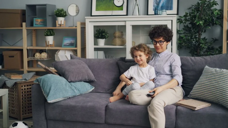 Mother and son sitting on a couch in a cozy living room, enjoying their time together. - home jumbotron