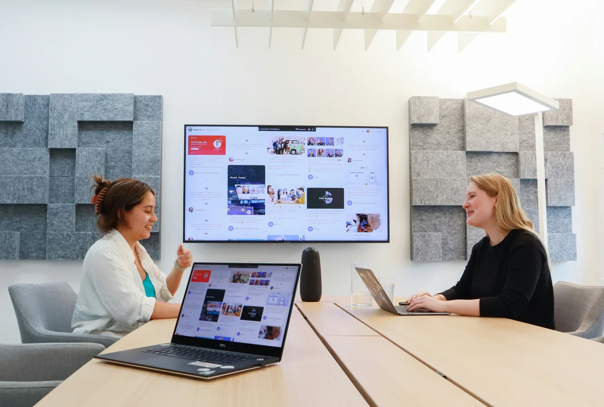 Two women having a meeting in an office with a screen on the wall - projection on wall vs screen