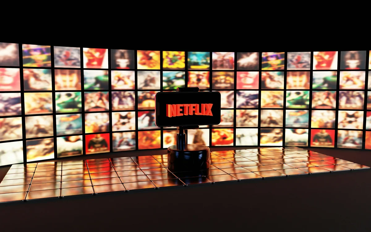 A smartphone displays the Netflix logo in bright red, set against a background of vibrant, colorful movie thumbnails and a glossy tiled surface. The cinematic atmosphere highlights streaming culture and digital entertainment. - projection on wall vs screen